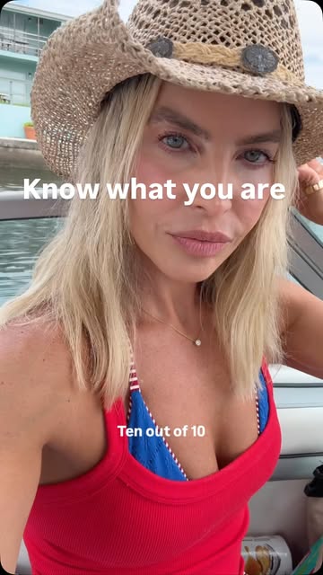 Melissa on a boat wearing a hat, filmed vertically on the water.